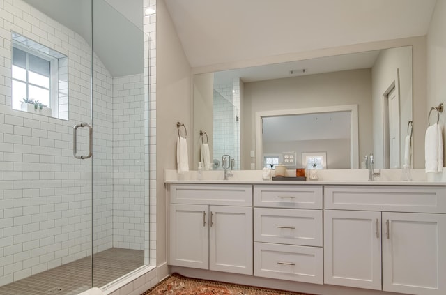 bathroom featuring a shower with door, large vanity, and double sink