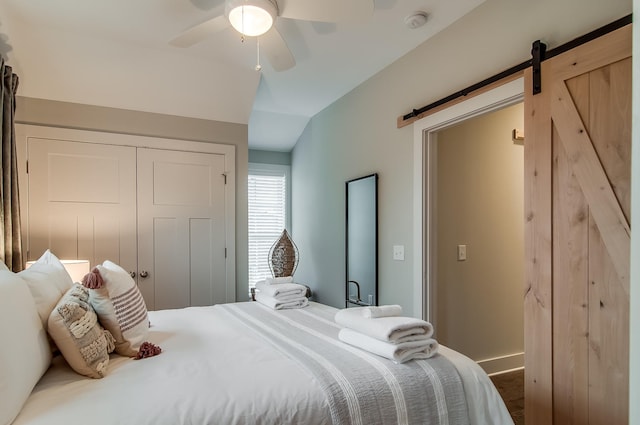 bedroom featuring a barn door, ceiling fan, a closet, and lofted ceiling