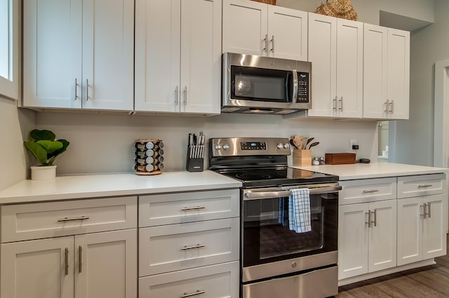 kitchen with hardwood / wood-style floors, white cabinetry, and appliances with stainless steel finishes