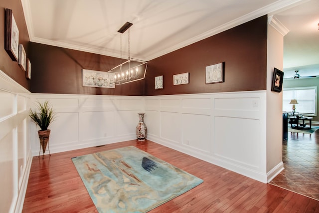 interior space with ceiling fan with notable chandelier, hardwood / wood-style flooring, and ornamental molding