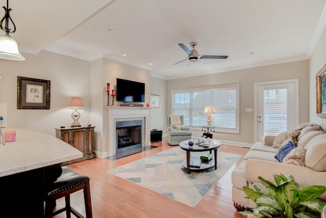 living room featuring ceiling fan, light hardwood / wood-style floors, and ornamental molding