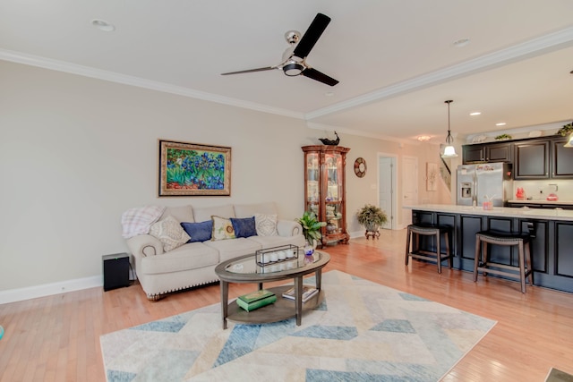 living room with light hardwood / wood-style floors, ceiling fan, and ornamental molding