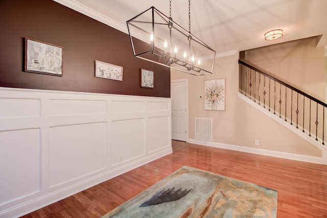 interior space with a chandelier, hardwood / wood-style floors, and ornamental molding