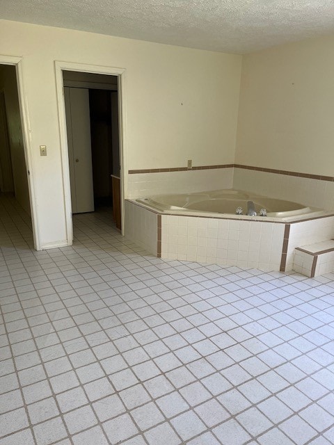 bathroom featuring tiled tub and a textured ceiling