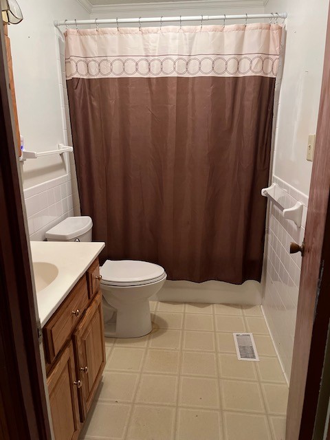 bathroom with vanity, toilet, and tile walls