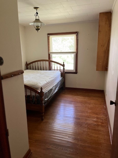 bedroom with dark hardwood / wood-style flooring and crown molding