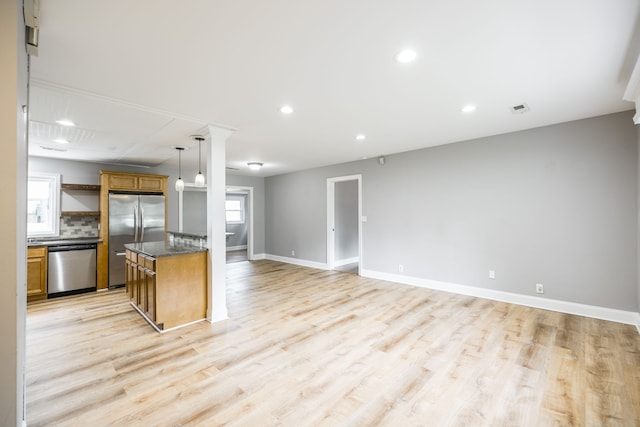 kitchen with a kitchen island, backsplash, decorative light fixtures, light wood-type flooring, and appliances with stainless steel finishes