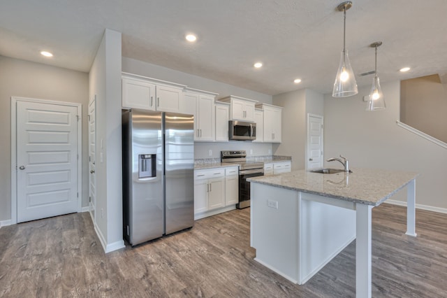 kitchen featuring a center island with sink, appliances with stainless steel finishes, white cabinetry, and hardwood / wood-style floors