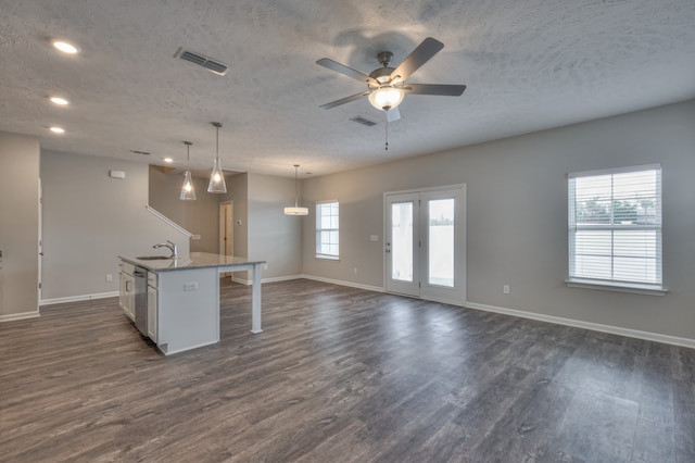 kitchen featuring pendant lighting, dark hardwood / wood-style flooring, sink, white cabinets, and a kitchen island with sink