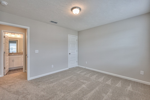 unfurnished bedroom with sink, a textured ceiling, and carpet