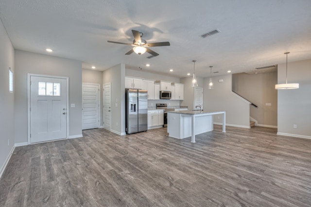 kitchen featuring decorative light fixtures, a kitchen island with sink, hardwood / wood-style flooring, and appliances with stainless steel finishes