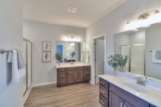 bathroom featuring dual vanity, a shower with door, and hardwood / wood-style flooring