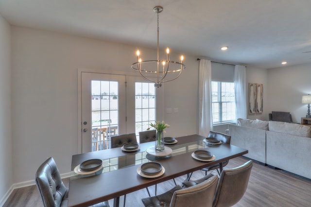 dining space with a healthy amount of sunlight, wood-type flooring, and a chandelier