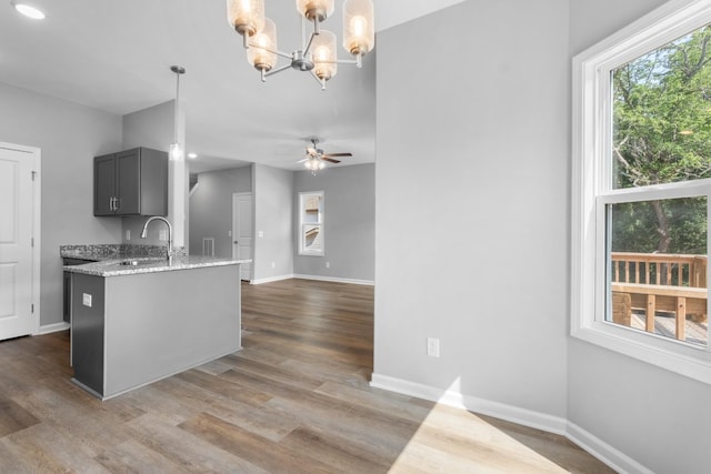 kitchen featuring gray cabinetry, hanging light fixtures, light stone countertops, and sink