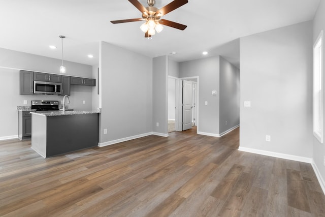 unfurnished living room with sink, dark hardwood / wood-style floors, and ceiling fan