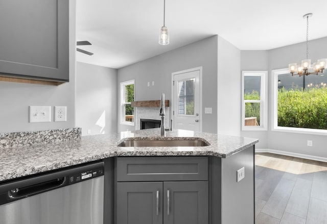 kitchen with ceiling fan with notable chandelier, stainless steel dishwasher, gray cabinets, and sink