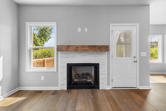 unfurnished living room featuring a fireplace, a wealth of natural light, and wood-type flooring