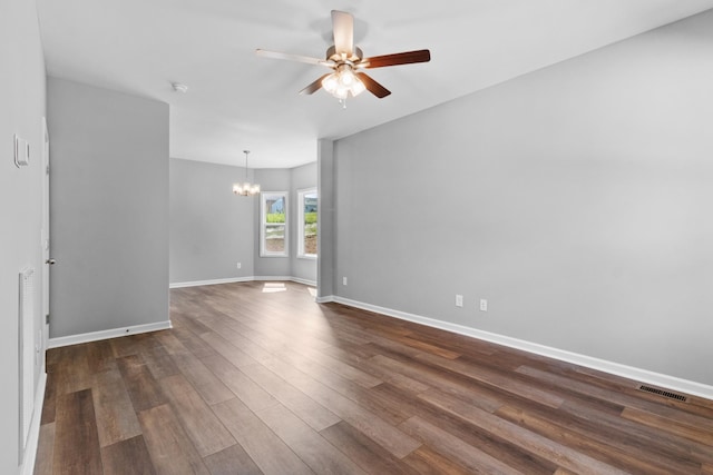 empty room featuring ceiling fan with notable chandelier and dark hardwood / wood-style floors