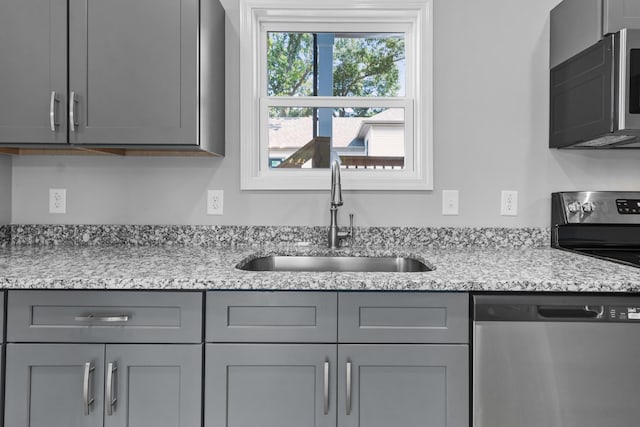 kitchen featuring gray cabinets, dishwasher, sink, and light stone countertops