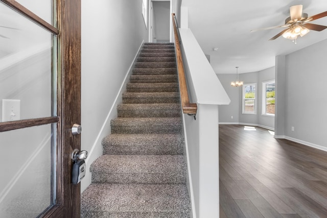 stairway with hardwood / wood-style floors and ceiling fan with notable chandelier