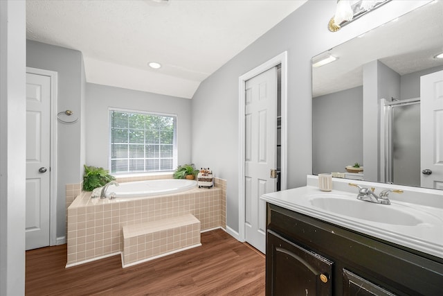 bathroom with hardwood / wood-style flooring, shower with separate bathtub, large vanity, a textured ceiling, and lofted ceiling