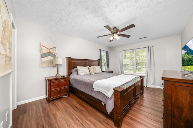 bedroom featuring hardwood / wood-style flooring, ceiling fan, and a textured ceiling