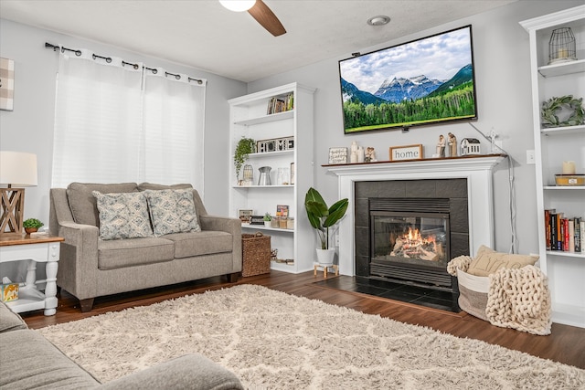 living room with a tiled fireplace, ceiling fan, and dark hardwood / wood-style floors