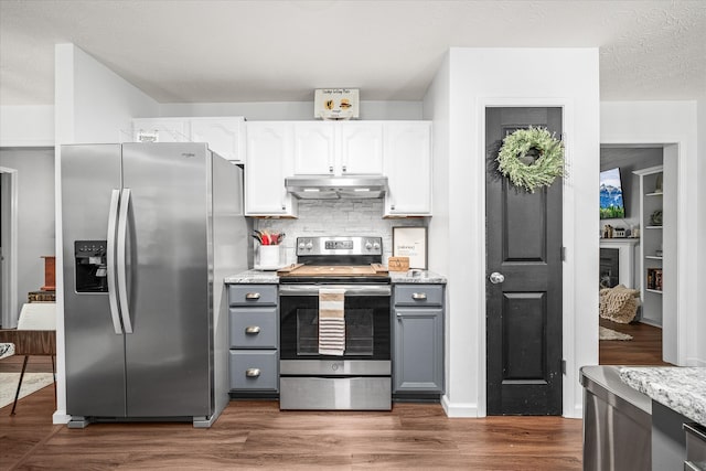 kitchen with dark hardwood / wood-style flooring, backsplash, gray cabinetry, white cabinets, and appliances with stainless steel finishes