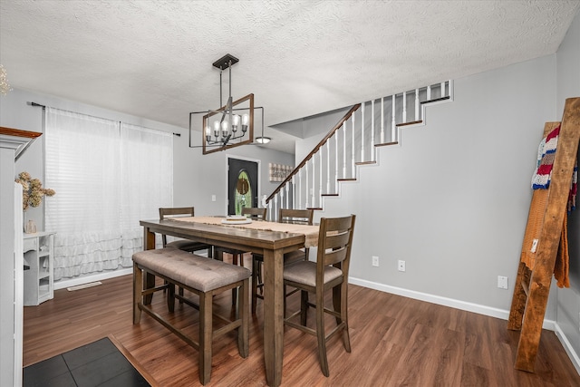 dining area featuring a chandelier, a textured ceiling, and dark hardwood / wood-style floors