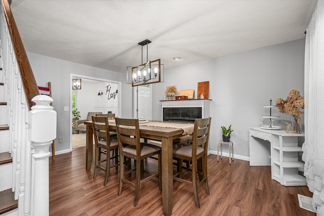 dining area featuring a textured ceiling, wood-type flooring, and an inviting chandelier