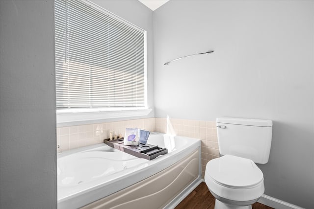 bathroom featuring wood-type flooring, toilet, a bath, and tile walls