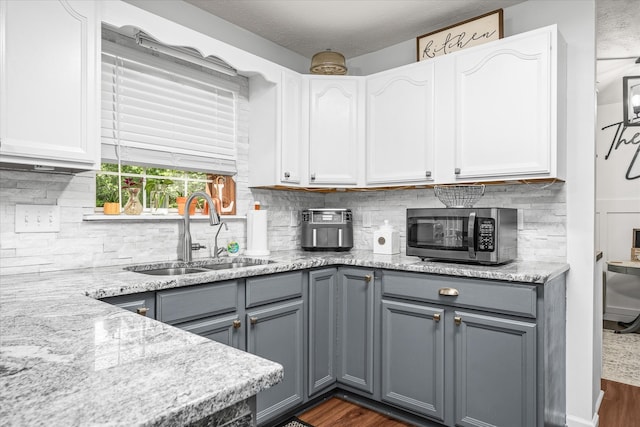 kitchen featuring dark wood-type flooring, gray cabinetry, sink, and tasteful backsplash