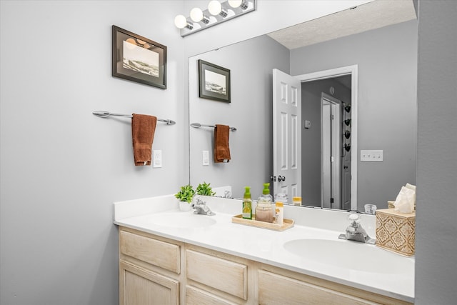 bathroom featuring a textured ceiling, large vanity, and dual sinks