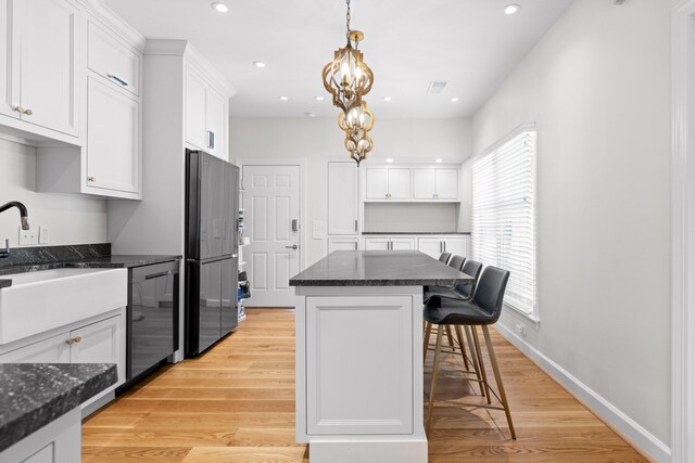 kitchen featuring stainless steel appliances, white cabinetry, a center island, and light hardwood / wood-style floors