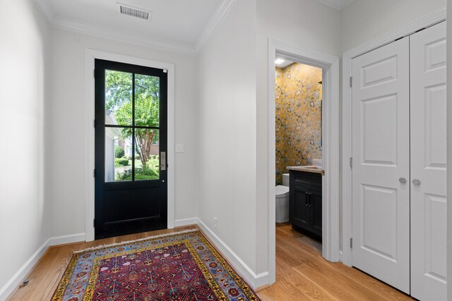 foyer entrance with light wood-type flooring and crown molding