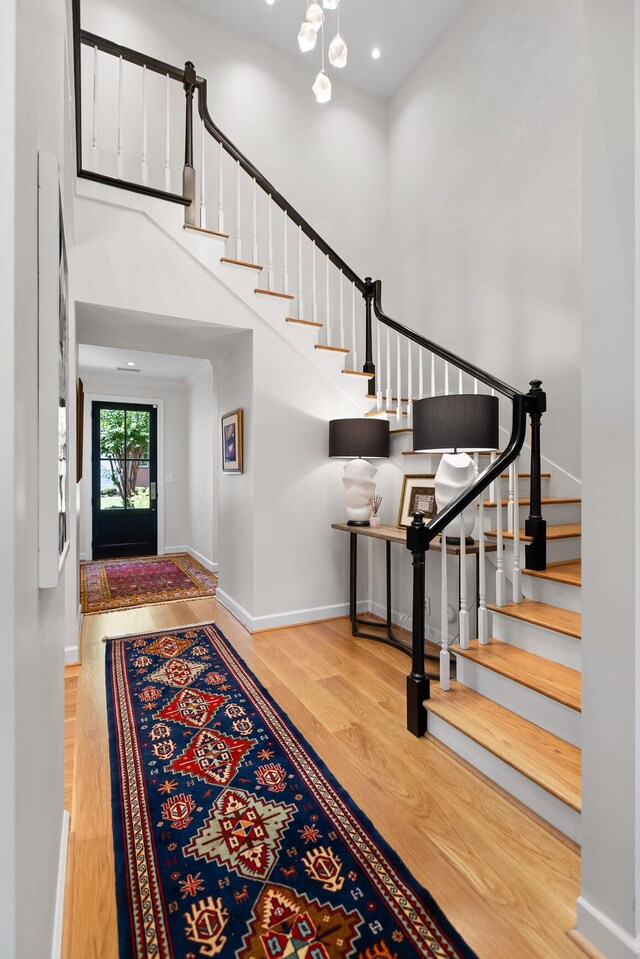 entrance foyer featuring a notable chandelier, hardwood / wood-style floors, and a towering ceiling