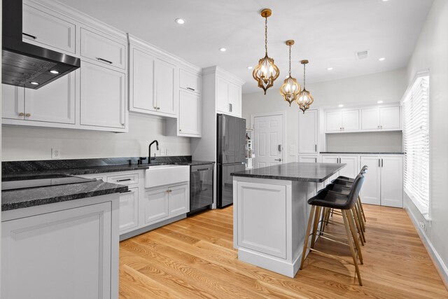 kitchen featuring hanging light fixtures, stainless steel appliances, light hardwood / wood-style floors, and a kitchen island