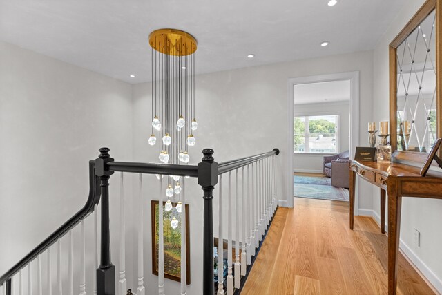 corridor with light hardwood / wood-style flooring and a chandelier