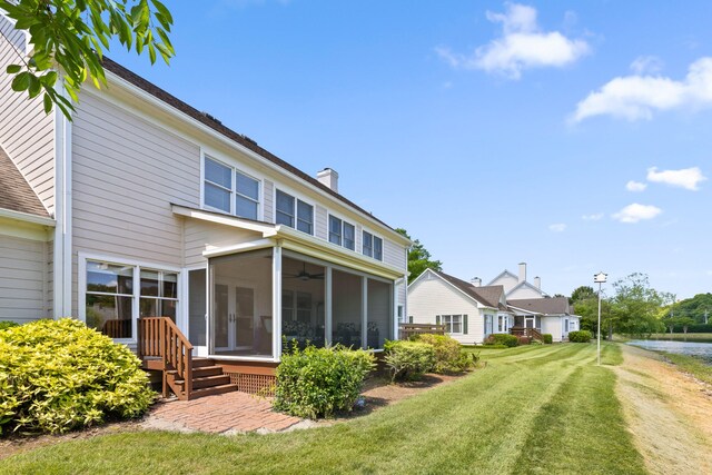 rear view of house featuring a sunroom and a lawn