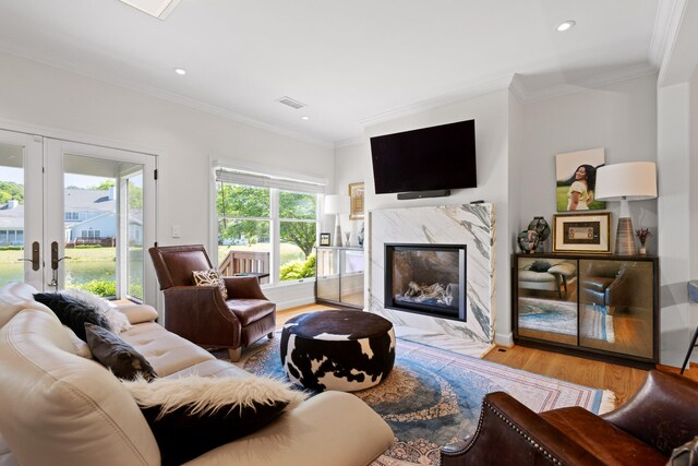 living room with a premium fireplace, french doors, wood-type flooring, and crown molding