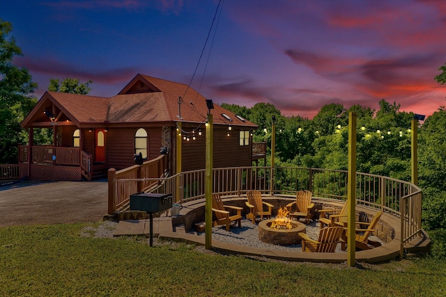 exterior space with a wooden deck, an outdoor fire pit, and a lawn