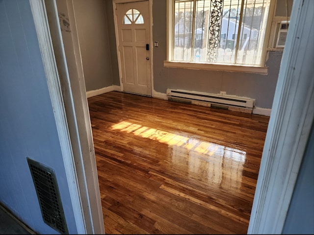 foyer entrance with a baseboard heating unit and dark wood-type flooring