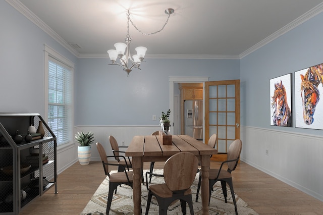 dining room featuring ornamental molding, light wood-type flooring, and a chandelier