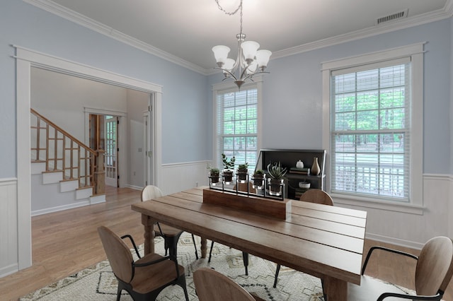 dining area with crown molding, a notable chandelier, and light hardwood / wood-style flooring