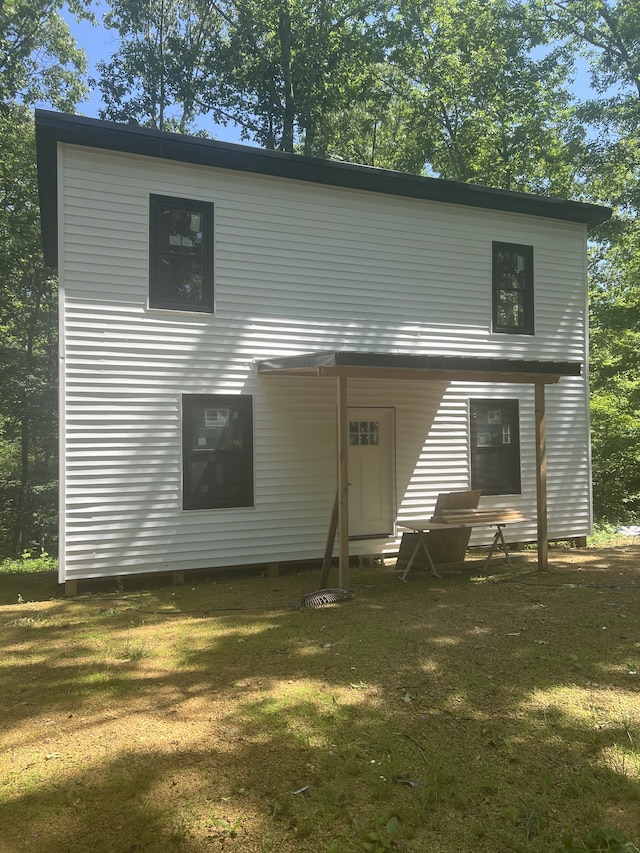 rear view of property featuring a lawn