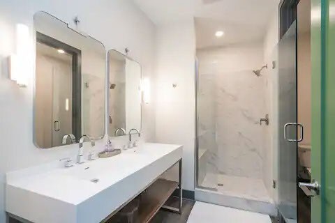 bathroom with a shower with shower door and large vanity