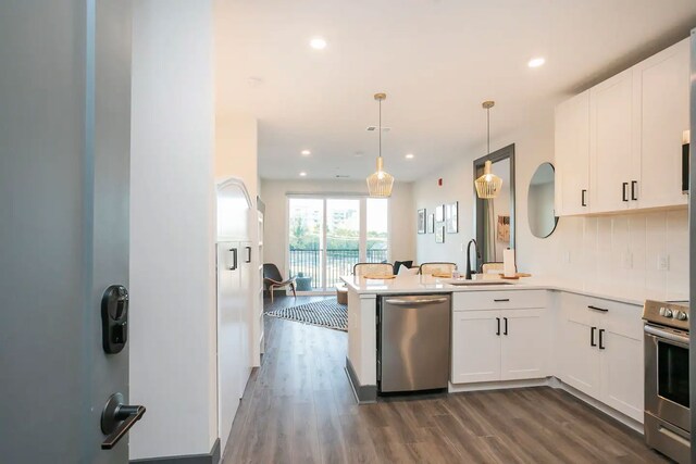 kitchen with kitchen peninsula, backsplash, range, stainless steel dishwasher, and wood-type flooring