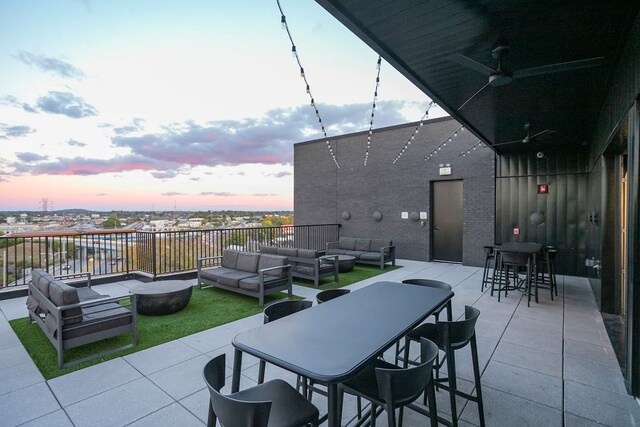 patio terrace at dusk with outdoor lounge area and ceiling fan