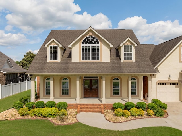 view of front of home with a garage, covered porch, and a front yard