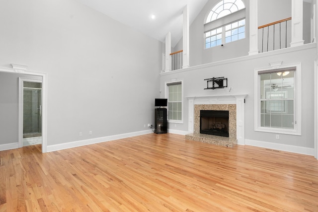 unfurnished living room featuring a premium fireplace, light hardwood / wood-style flooring, and high vaulted ceiling